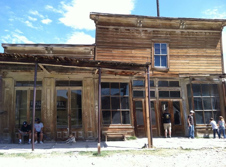 Empty old rustic storefront with large windows and weathered wood, attracting visitors and tourists, located in a historic town or ghost town; vintage western architecture.