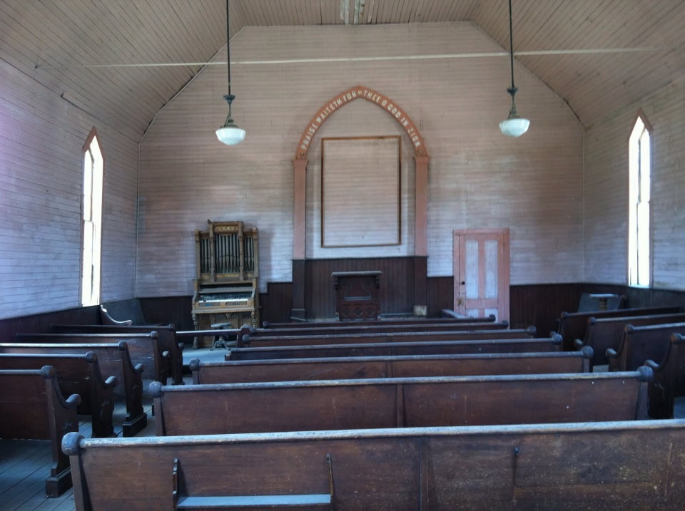 Simple church interior with wooden pews and hymnals, evoking a peaceful worship space for community gatherings and spiritual reflection.