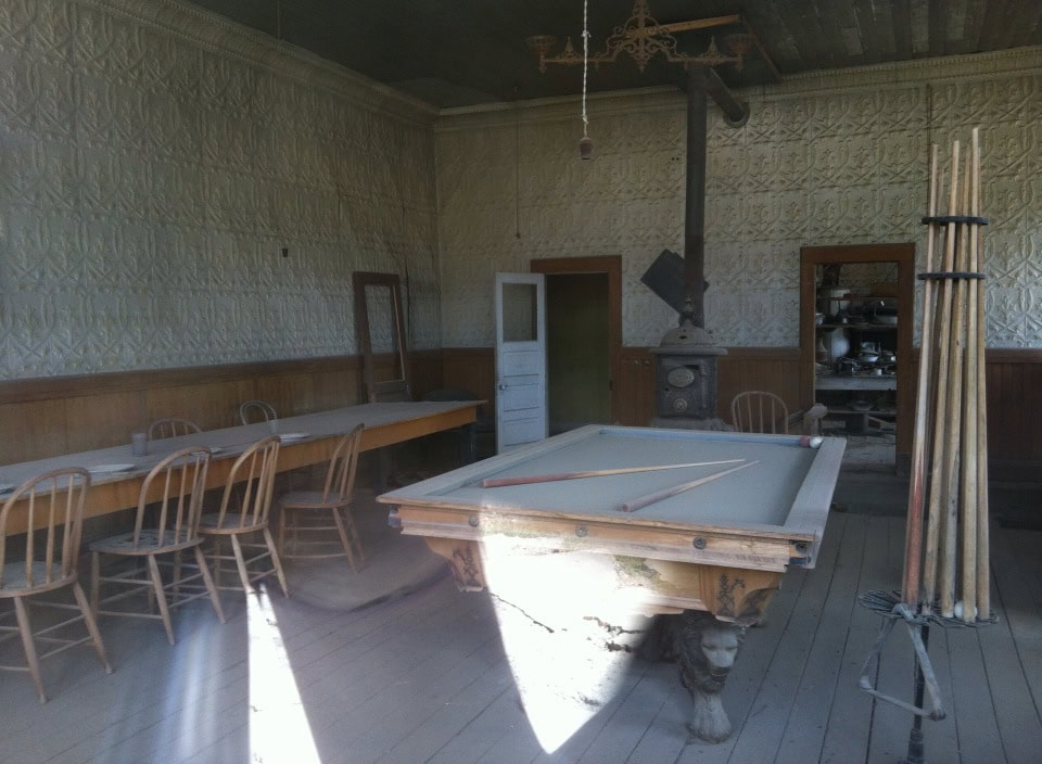 Antique rustic game room with vintage pool table, wooden chairs, and cozy ambiance, perfect for leisure and gatherings.