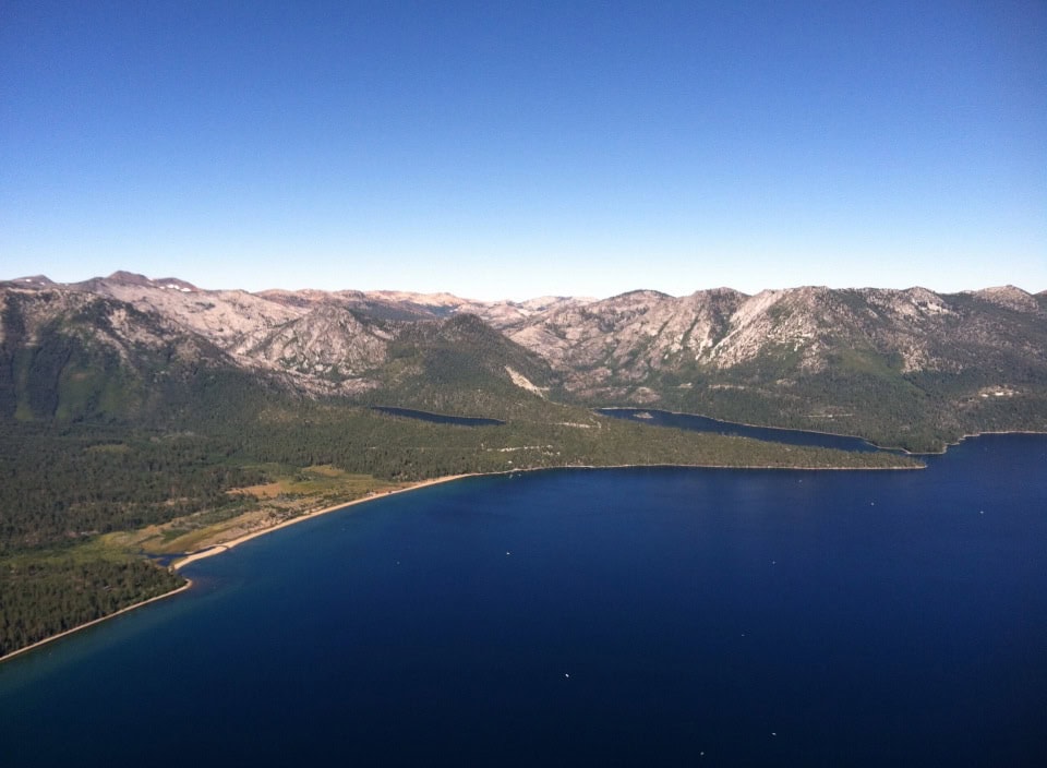 Vast mountain lake with clear blue water surrounded by rugged mountains and lush forest, scenic outdoor nature landscape, eco-friendly travel destination, A Hundred Affections.