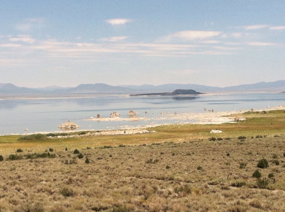 Serene landscape with calm lake, distant mountains, and open skies, perfect for nature lovers and outdoor enthusiasts.