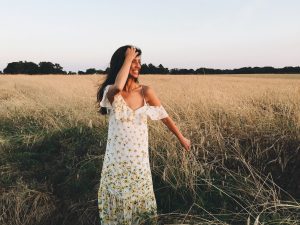 Vibrant woman in a floral dress enjoying a sunny day in a golden wheat field, capturing moments of joy, nature, summer fashion, and outdoor serenity.