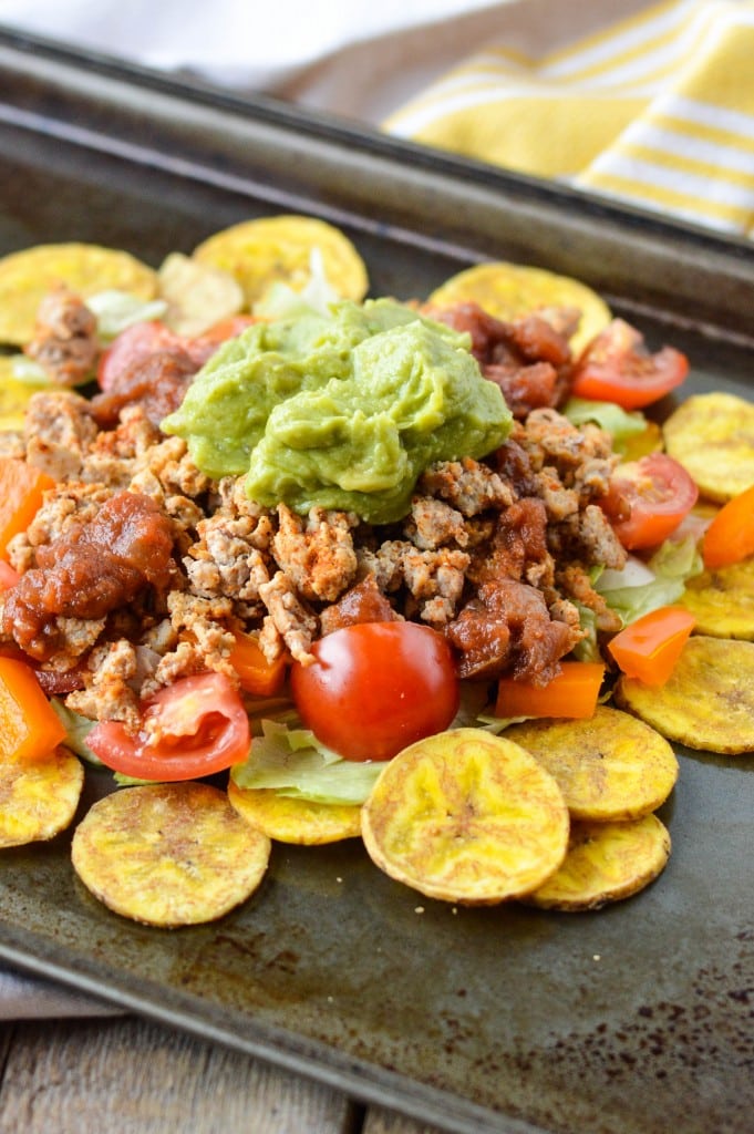Savory Nachos with Ground Beef and Guacamole on a rustic plate with roasted plantains, fresh vegetables, and shredded lettuce, perfect for easy Mexican-inspired snacks or meals.