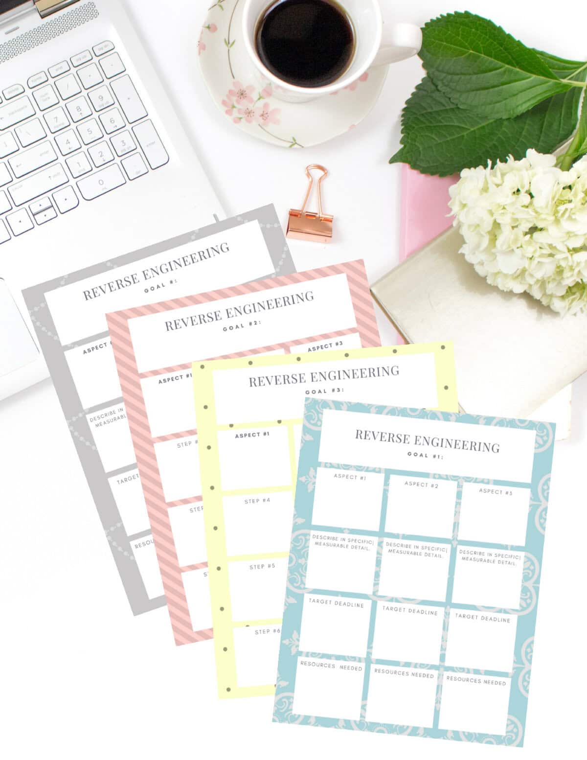 Colorful reverse engineering goal sheets for project planning, business strategy, and goal tracking, with a laptop, coffee, flowers, and stationery on a white desk.