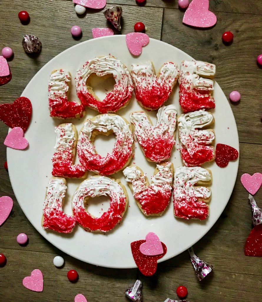 White plate with LOVE cookies 3x with heart and candy....Anything ombre is a fan favorite these days!  For a trendy sweet Valentine's Day treat, try these Ombre LOVE Sugar Cookies - with a free printable ombre "Love is Patient & Kind" gift tag to match!