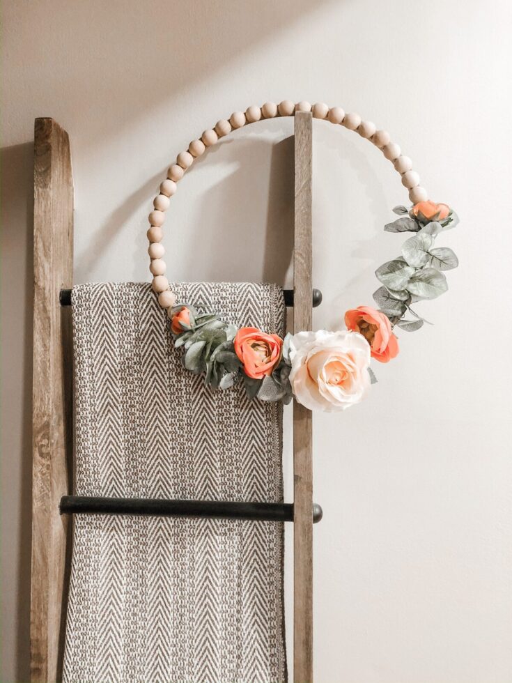 Handmade flower and bead wreath with roses and greenery, perfect for home decor or special occasions.