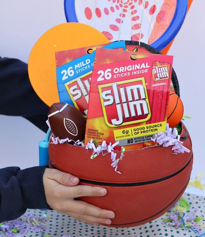 A colorful Easter basket filled with sports-themed toys, Slim Jim snacks, and decorative Easter eggs, perfect for celebrating spring and Easter festivities.