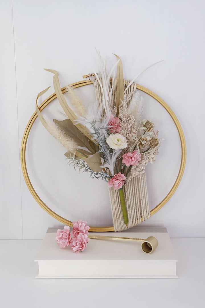 Elegant dried flower arrangement with neutral tones, pampas grass, and pink accents, displayed in a modern ring wall decor piece, perfect for home decor or gift ideas.