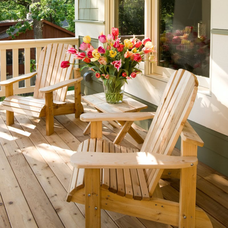 spring porch with adirondack chairs and fresh flowers in vase on table