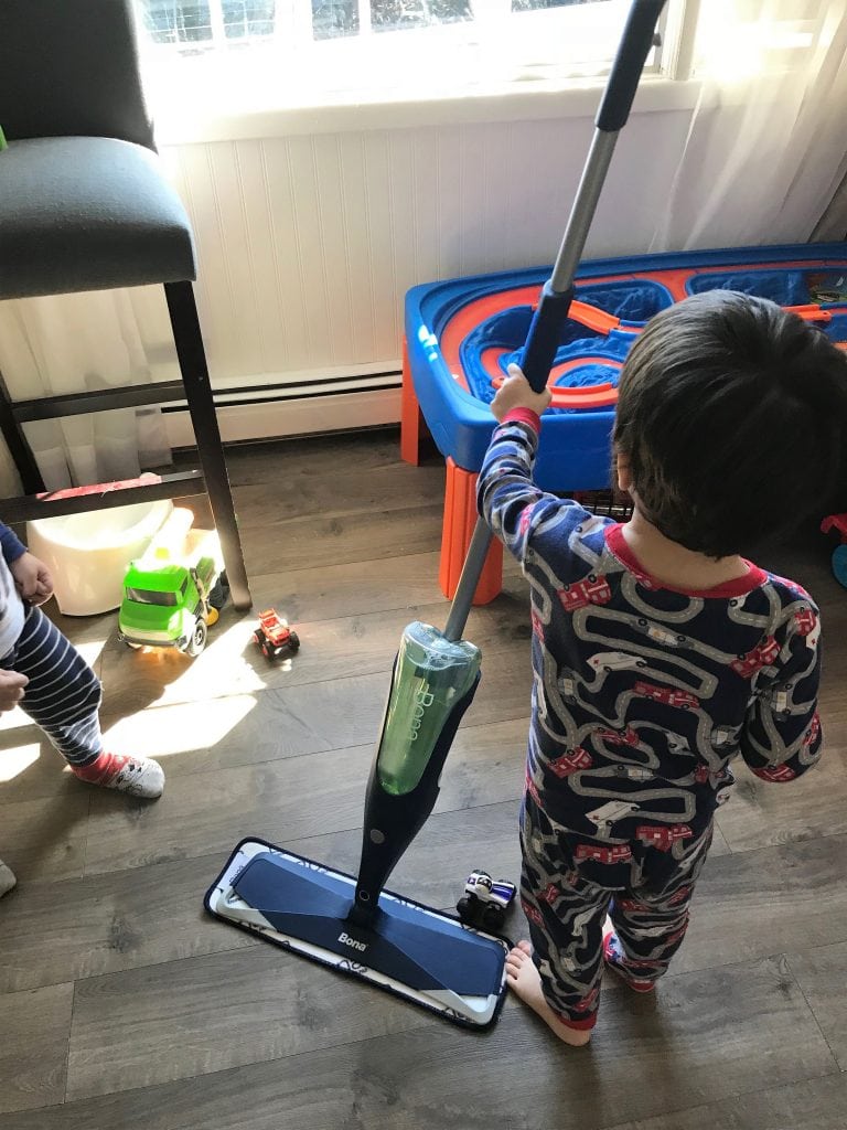Colorful children's toy hockey stick and miniature cars playing on wooden floor.