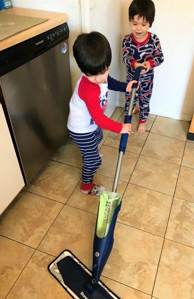 Kids playing with a toy vacuum cleaner in a cozy home setting.