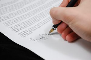 Elegant hand signing a wedding or love letter with a fountain pen, symbolizing romance and heartfelt sentiments, perfect for love and relationship-themed content.