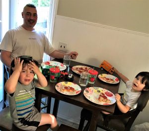 Happy family pizza night with kids and father, playful children with their dad, family fun, casual indoor setting, kids with toys and pizza, family bonding moment, home lifestyle.
