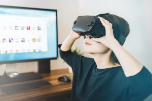Virtual reality headset being worn by woman at computer desk, showcasing immersive VR experience.