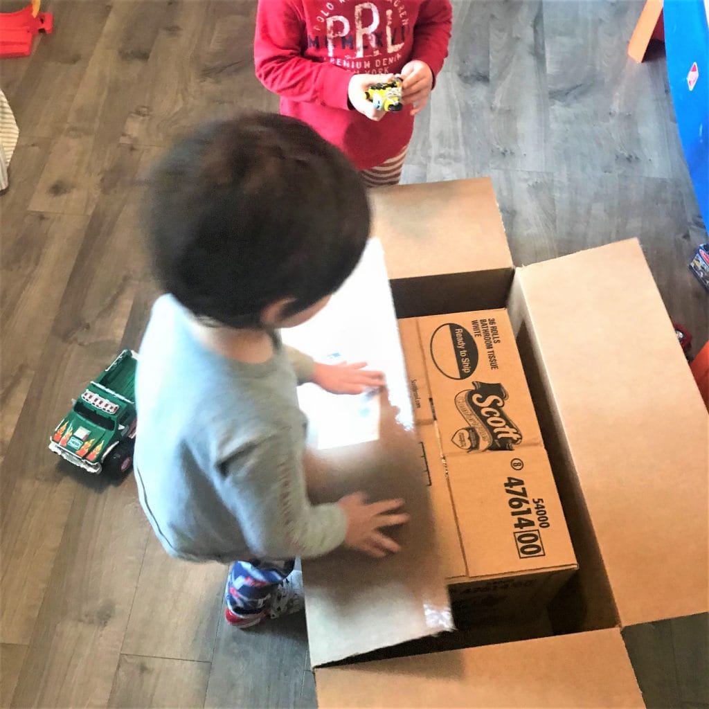 Bright children's toy truck and cardboard boxes for creative play, indoor kids activity, family fun, imaginative games, playful environment, children's toys, kids packing activity, kids at play.