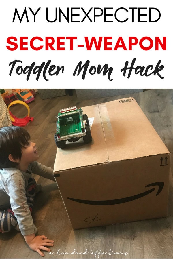 Little boy playing with a toy truck on a large Amazon box, showcasing a toddler mom hack for creative play and surprises.