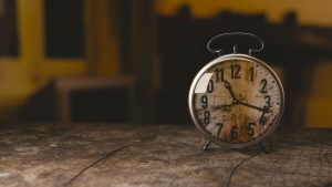 Vintage alarm clock with rusted face on rustic wood surface, nostalgic home decor, timekeeping, shabby chic style.
