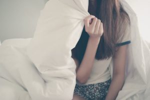 Comfortable woman in bed with cozy blanket, relaxing and enjoying a peaceful morning at home.