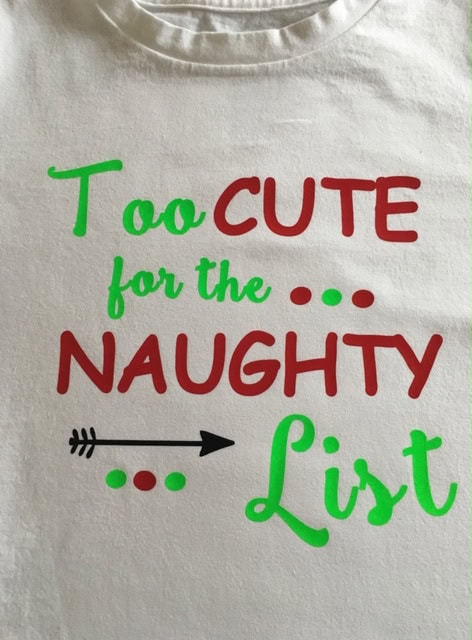 Brightly colored graphic T-shirt with playful holiday quote design, perfect for Christmas or casual wear, featuring bold red and green text and decorative elements.