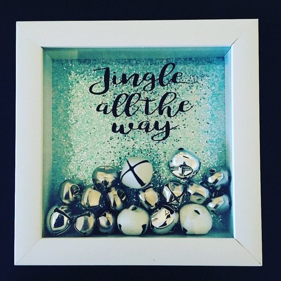 Shiny silver jingle bells with a festive "Jingle all the way" sign in decorative shadow box for Christmas holiday decor.