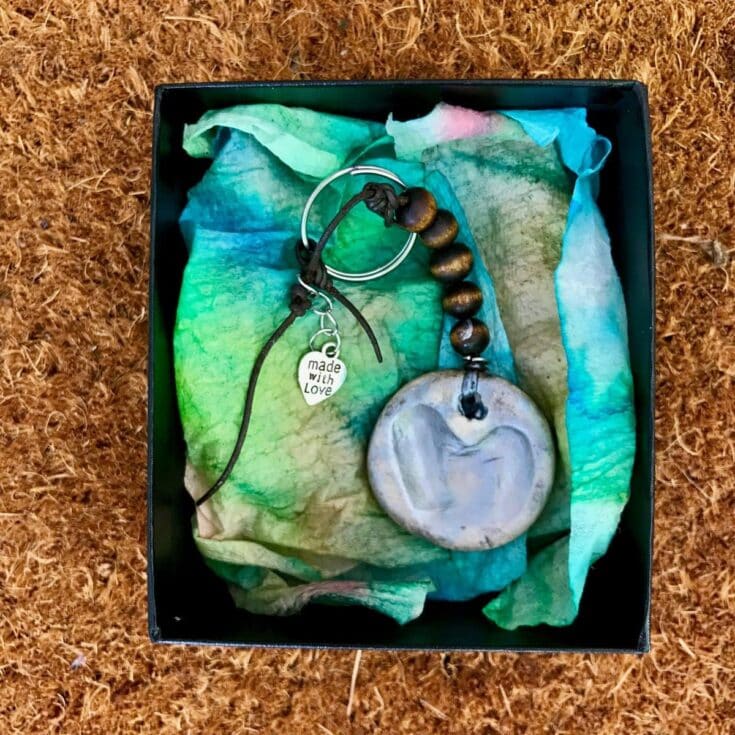 Handmade ceramic heart necklace with wooden beads and "made with love" charm in a gift box on tissue paper, perfect for heartfelt gifts and special occasions.
