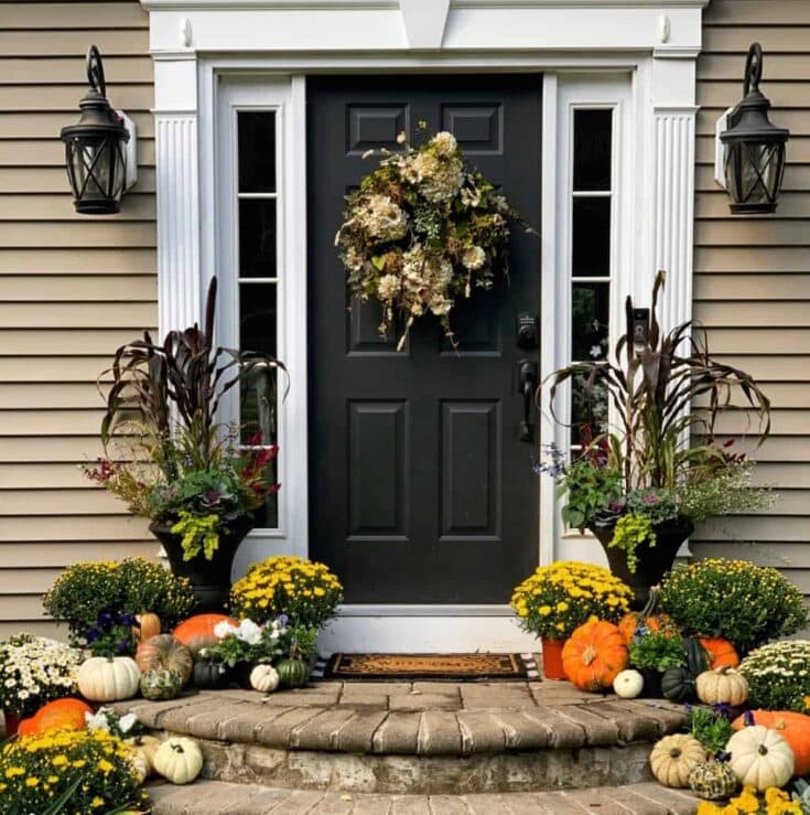 Vibrant fall front porch decorated with pumpkins, mums, and seasonal floral arrangements, showcasing cozy autumn decor for welcoming guests.