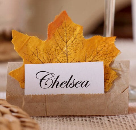 A decorated place card with a yellow autumn leaf for a fall wedding or event, featuring elegant calligraphy with the name Chelsea.