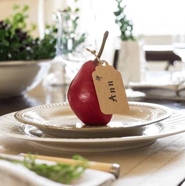 Fresh red apple with a handwritten gift tag reading "Anna" on an elegant table setting, ideal for personalized gifts, holiday decor, or wedding table arrangements.