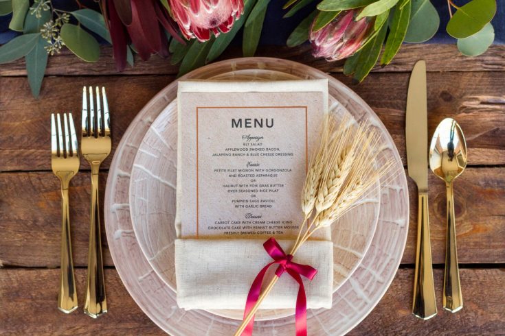 Elegant rustic wedding table setting with gold flatware, a menu card, and floral decorations for a romantic event.