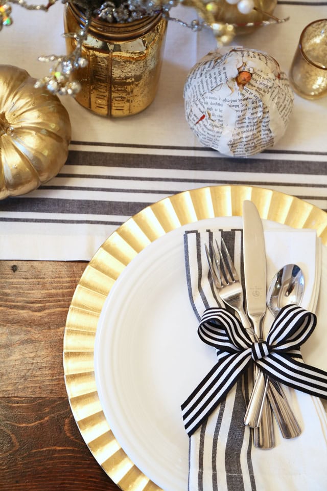 Elegant holiday table setting with gold accents and black-and-white striped details, perfect for festive gatherings and special occasions.