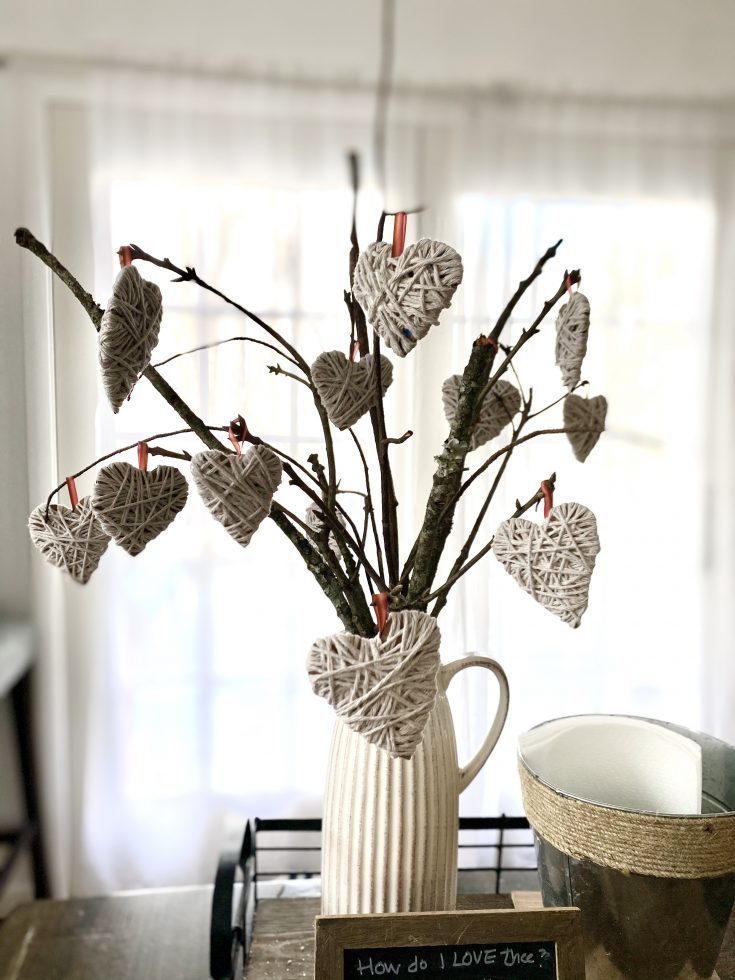 Valentine's Day decor with branches in farmhouse pitches and yarn hearts hung