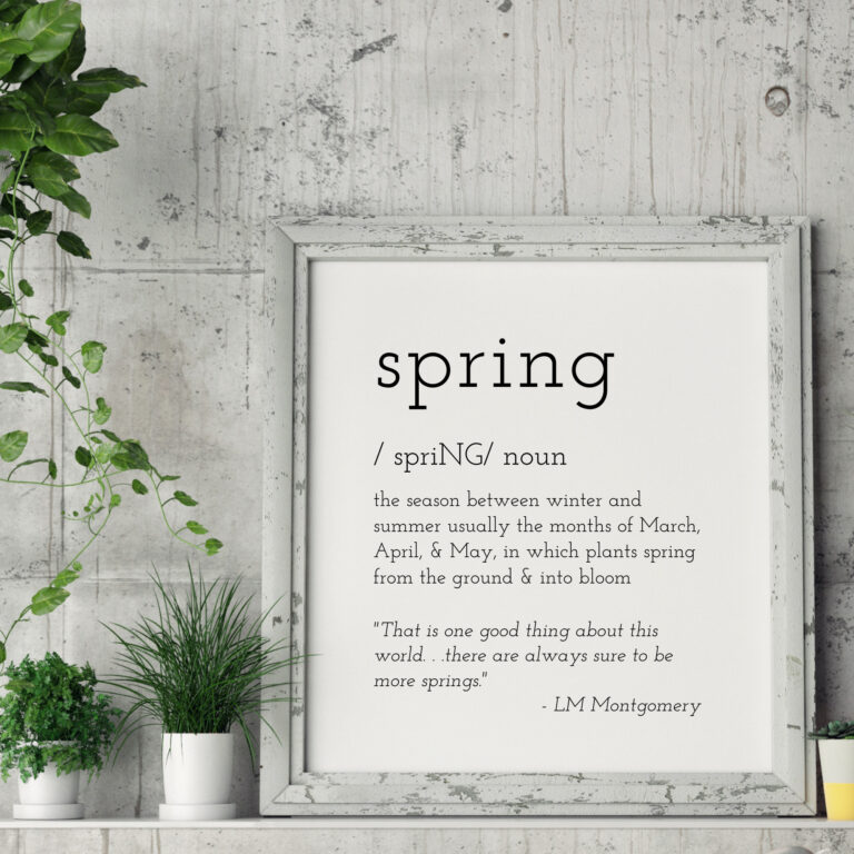 Vivid spring season quote framed art with indoor plants on rustic wooden background.
