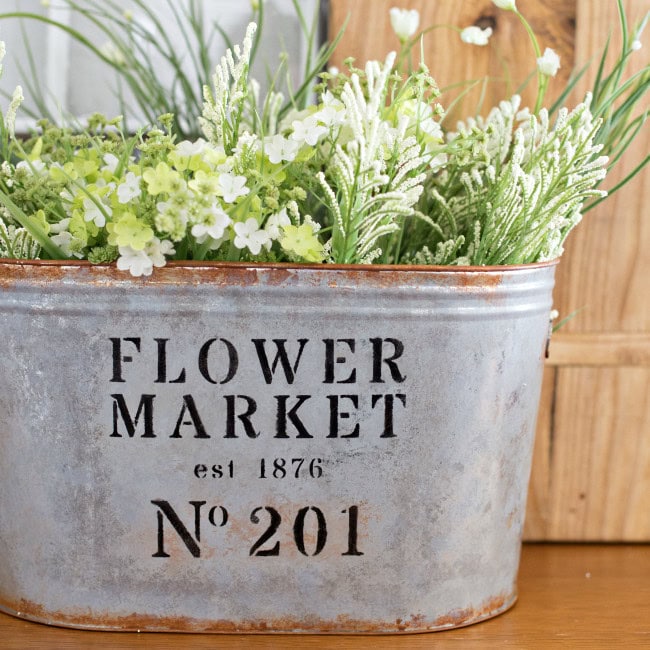 Vintage flower market metal planter with fresh white and green floral arrangement.