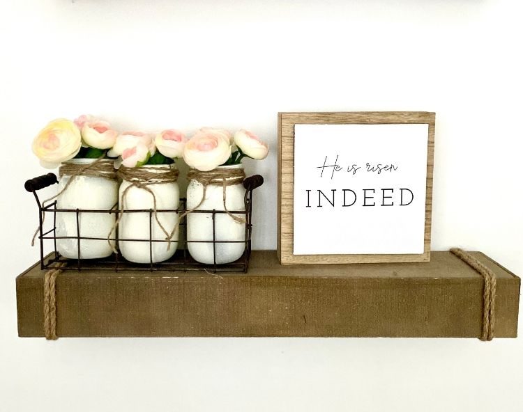 He is Risen farmhouse DIY sign next to mason jars with pink rosebuds