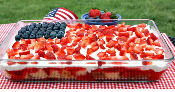 Fresh berry cream dessert in a glass baking dish with strawberries and blueberries for patriotic 4th of July celebration.