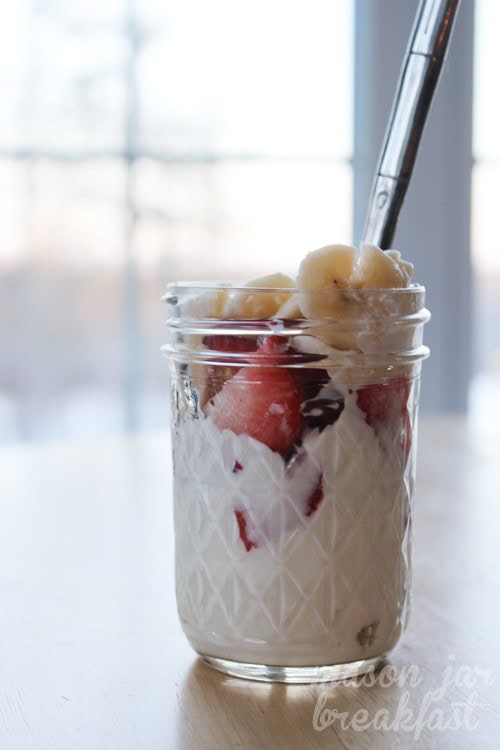 Fresh strawberry banana yogurt parfait in a glass jar with a spoon, perfect healthy breakfast or snack from A Hundred Affections.