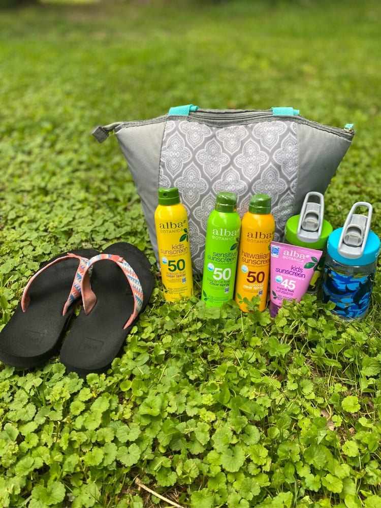 Brightly colored sunscreen bottles and flip-flops on lush green grass, showcasing summer essentials for kids' outdoor protection and fun.