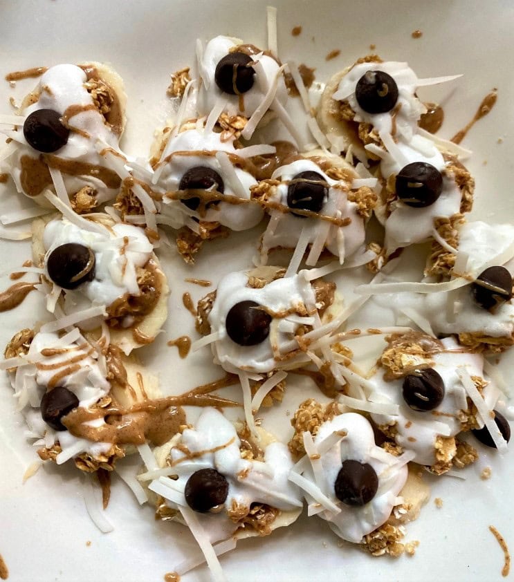 Banana pudding bites with whipped cream, chocolate chips, and shredded coconut on a white plate.