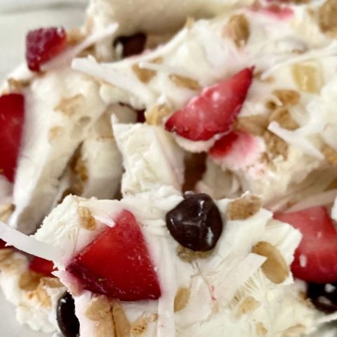 Sweet strawberry and blueberry cream dessert with toasted nuts and white chocolate shavings, perfect for summer treats and special occasions.