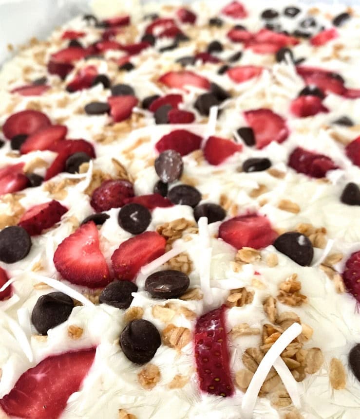 Fresh berry parfait with strawberries, blueberries, coconut flakes, and granola on a creamy white dessert base.