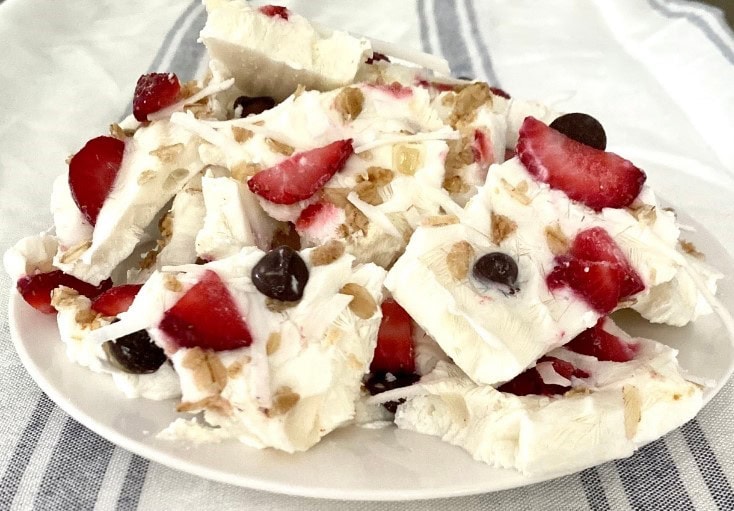 Fresh berry-white chocolate bark with strawberries, blueberries, and almonds on a white plate.
