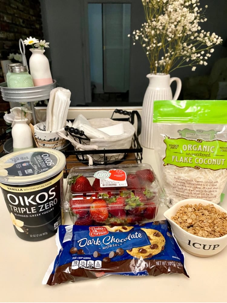Fresh strawberries, organic flake coconut, Greek yogurt, dark chocolate cookies, and granola for healthy breakfast options or snack ideas.