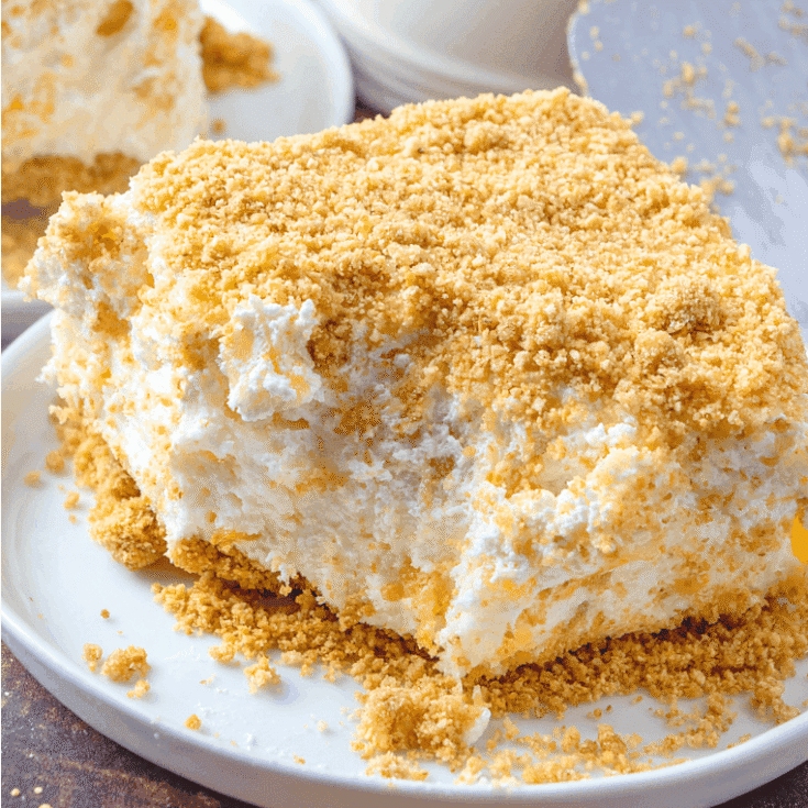 Fluffy lemon icebox cake with a crisp graham cracker crust and creamy filling, topped with golden crumbs, perfect for summer dessert.