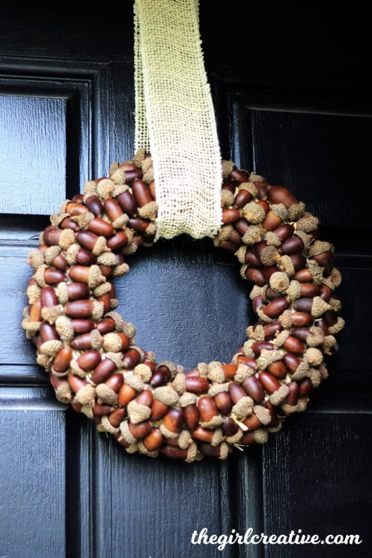 Acorn and burlap autumn fall wreath hanging on a black door for seasonal home decor.