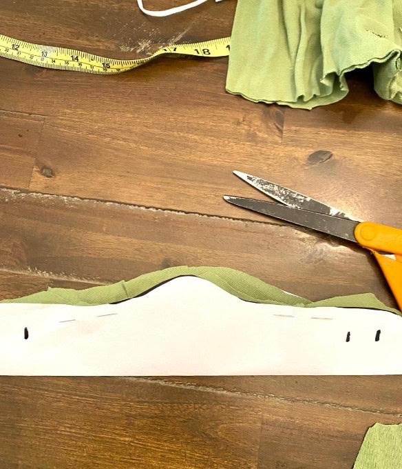 Molded fabric piece for sewing project with scissors and measuring tape on wooden table.