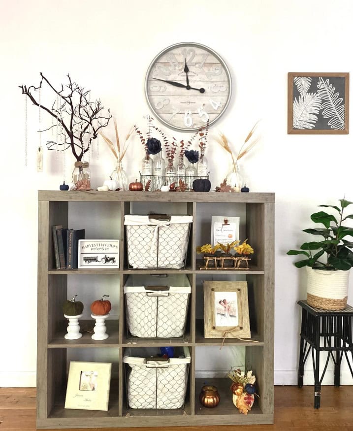 Vintage rustic wooden storage shelf decorated with autumn-themed ornaments and dried flowers, perfect for cozy home decor.