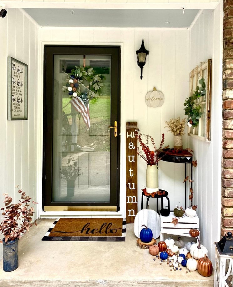 Cozy fall porch decor with autumn pumpkins, welcomes with "hello" doormat, harvest-themed accents, and seasonal foliage for a warm and inviting home entrance.