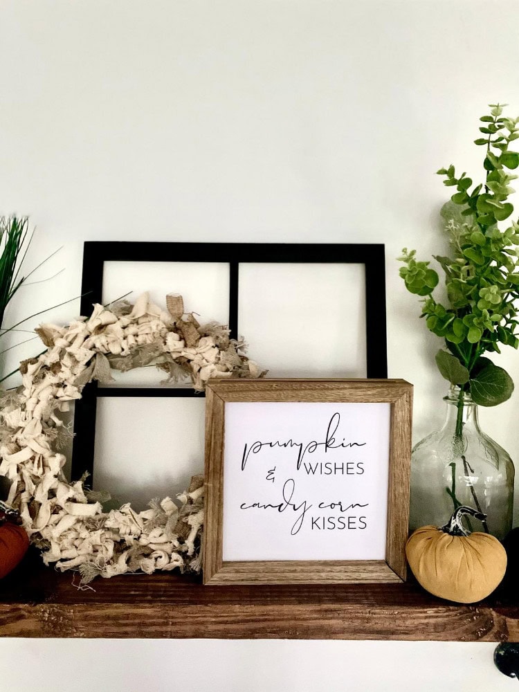 neutral rag wreath for fall styled on shelf with 'pumpkin wishes' sign with black window pane