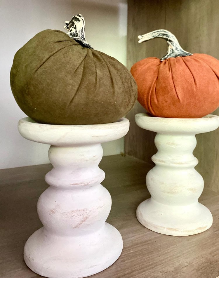 Rustic pumpkin decor with plush fabric textures on vintage white wooden pedestals for fall or Halloween decorations.