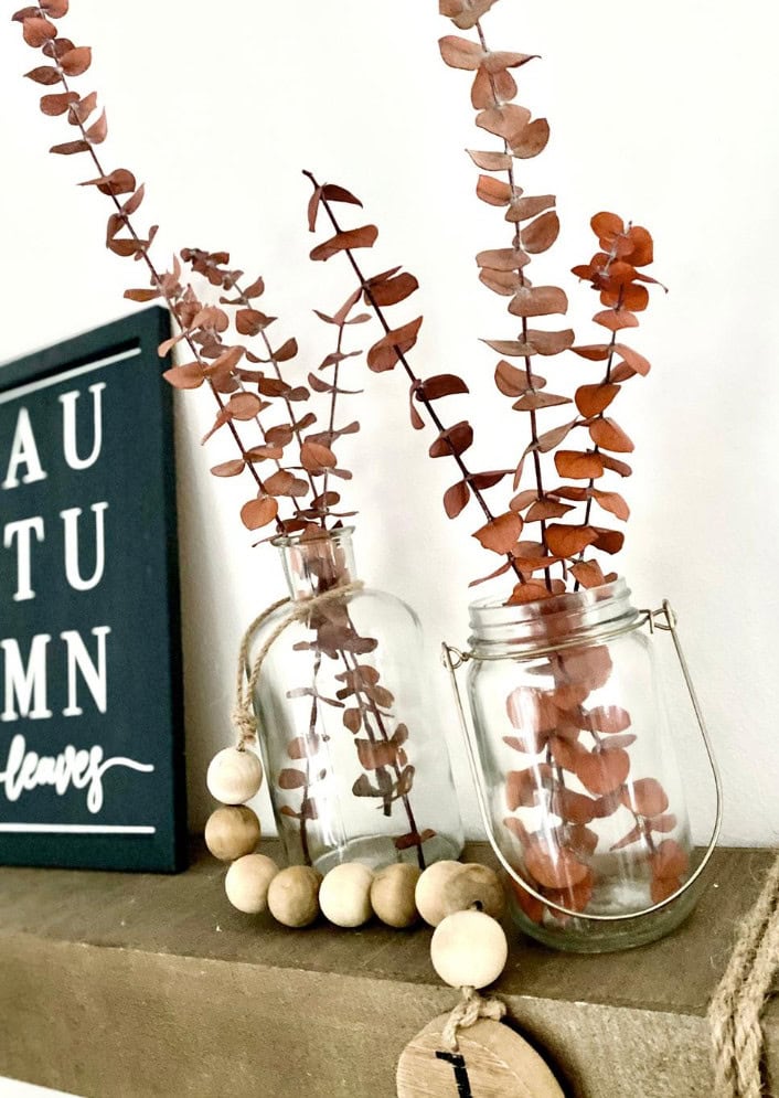 Dried eucalyptus branches in glass vases with neutral decor, perfect for rustic and modern home decor accents.